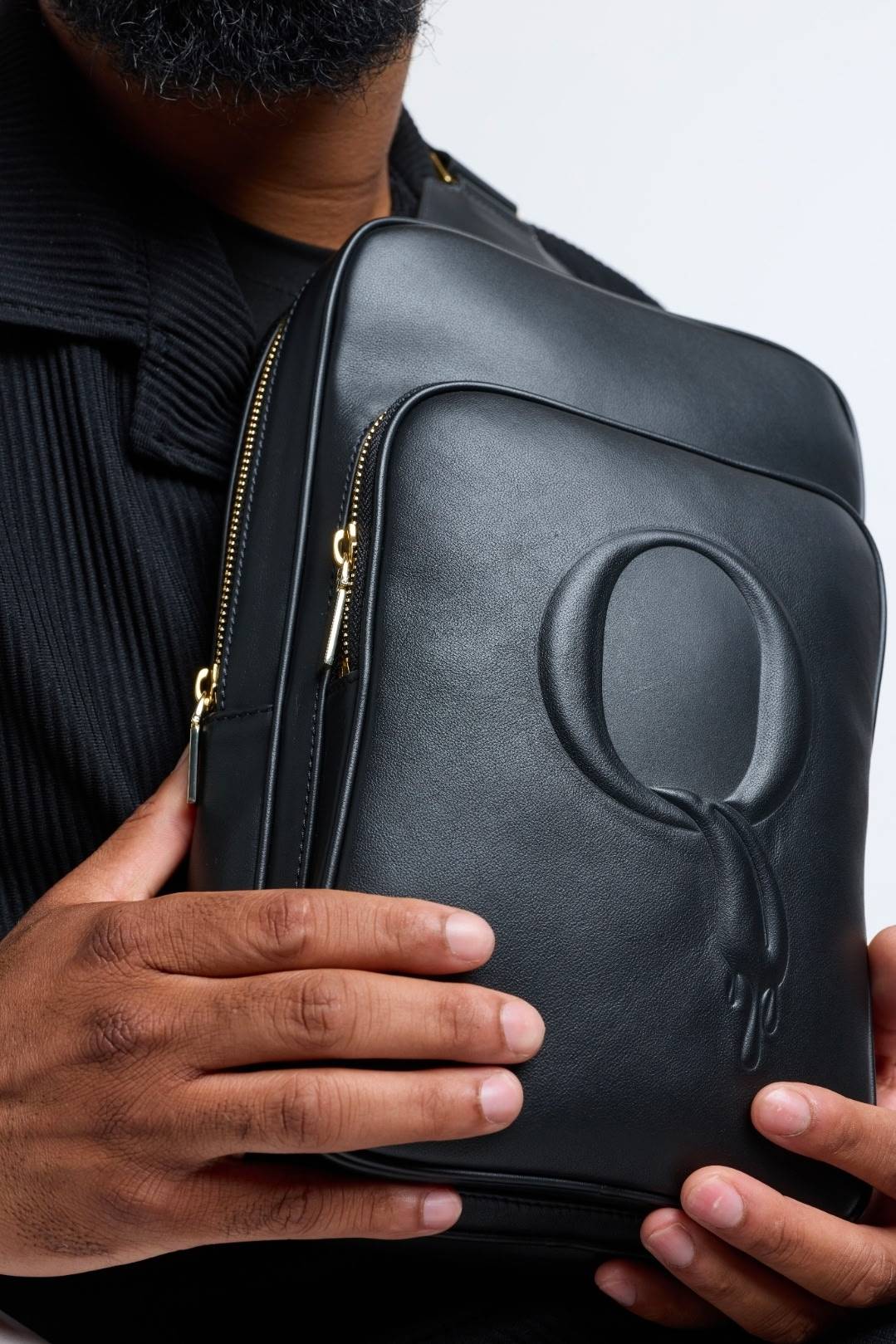 Close-up of the embossed melting Q on black leather